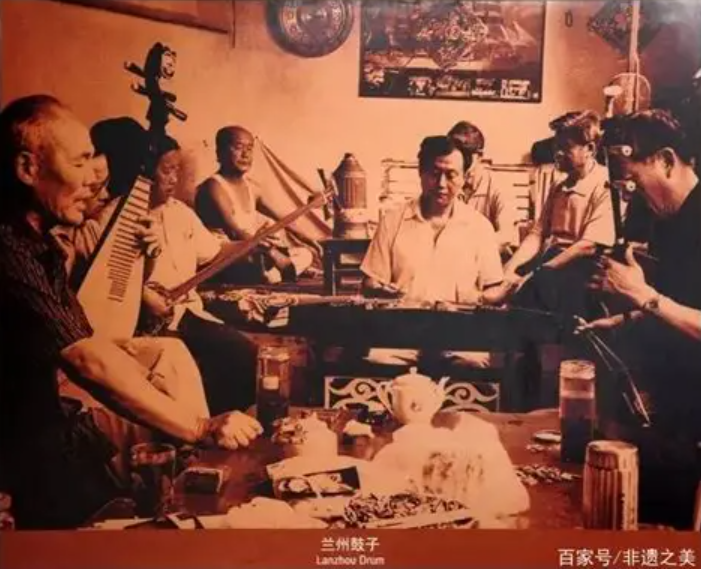 兰州鼓子表演，老艺人手持八角鼓弹唱，身着传统服饰，伴奏乐队使用三弦扬琴等民族乐器