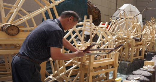 黄河水车制作技艺展示，工匠正在组装巨大的木质水车部件，展现传统榫卯工艺的精湛